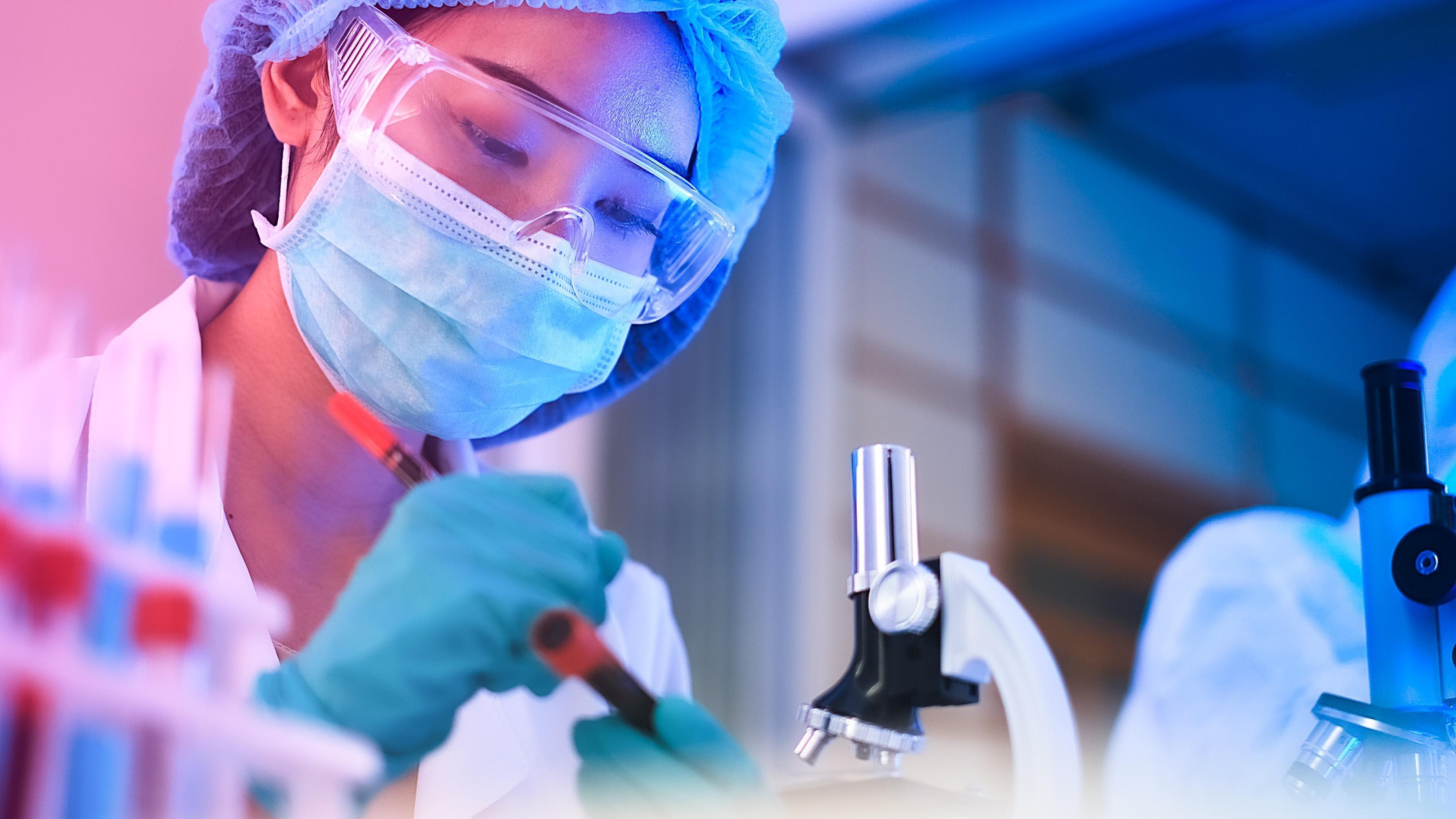 Eine Laborantin, die einen Rohstoff an einem Mikroskop untersucht